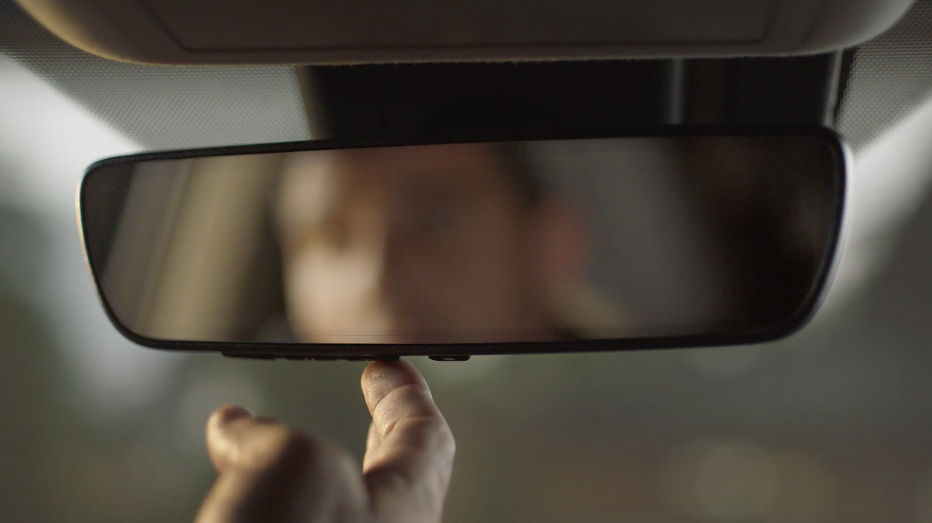 image of man pressing HomeLink button on rearview mirror